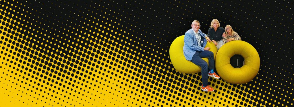 Myyntivimma-hankkeen hankekuva. 3 henkilöä makoilee donitsinmuotoisten istuimien päällä. Kuvaus taustalla keltamustia pikseleitä.